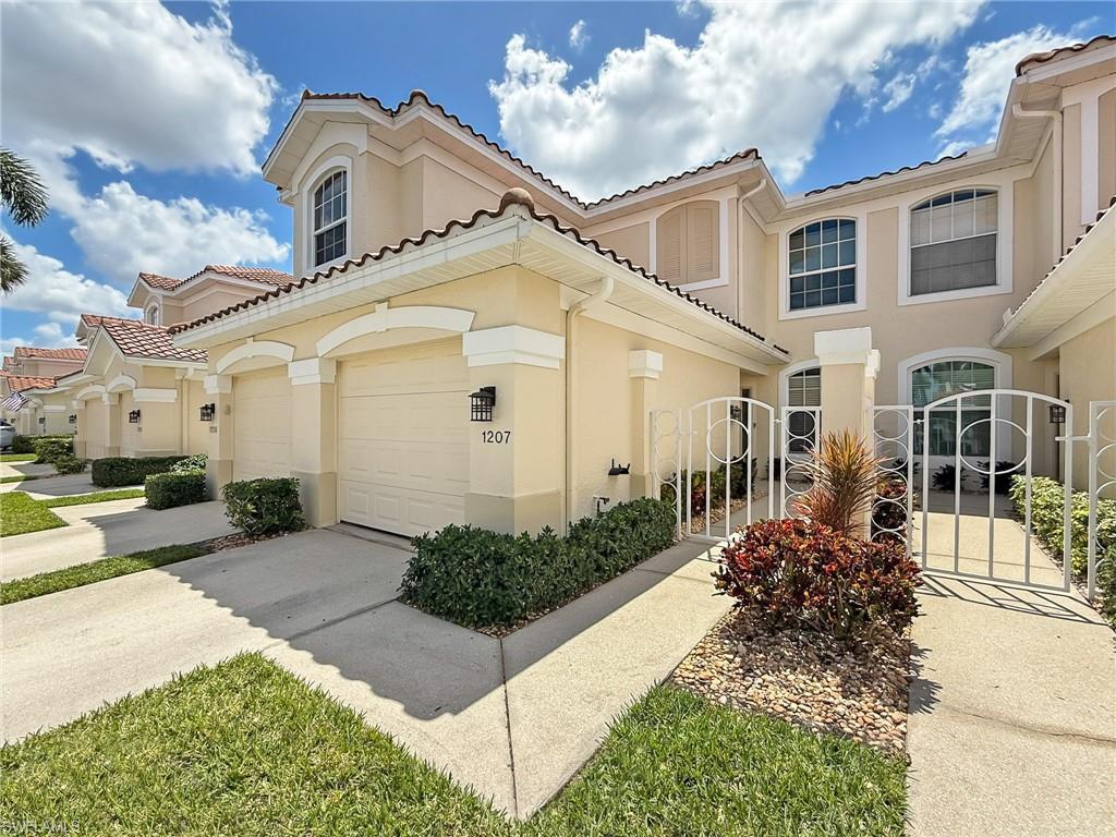 Image 2: Mediterranean / spanish-style home featuring a gate, fence, stucco siding, a tile roof, and driveway