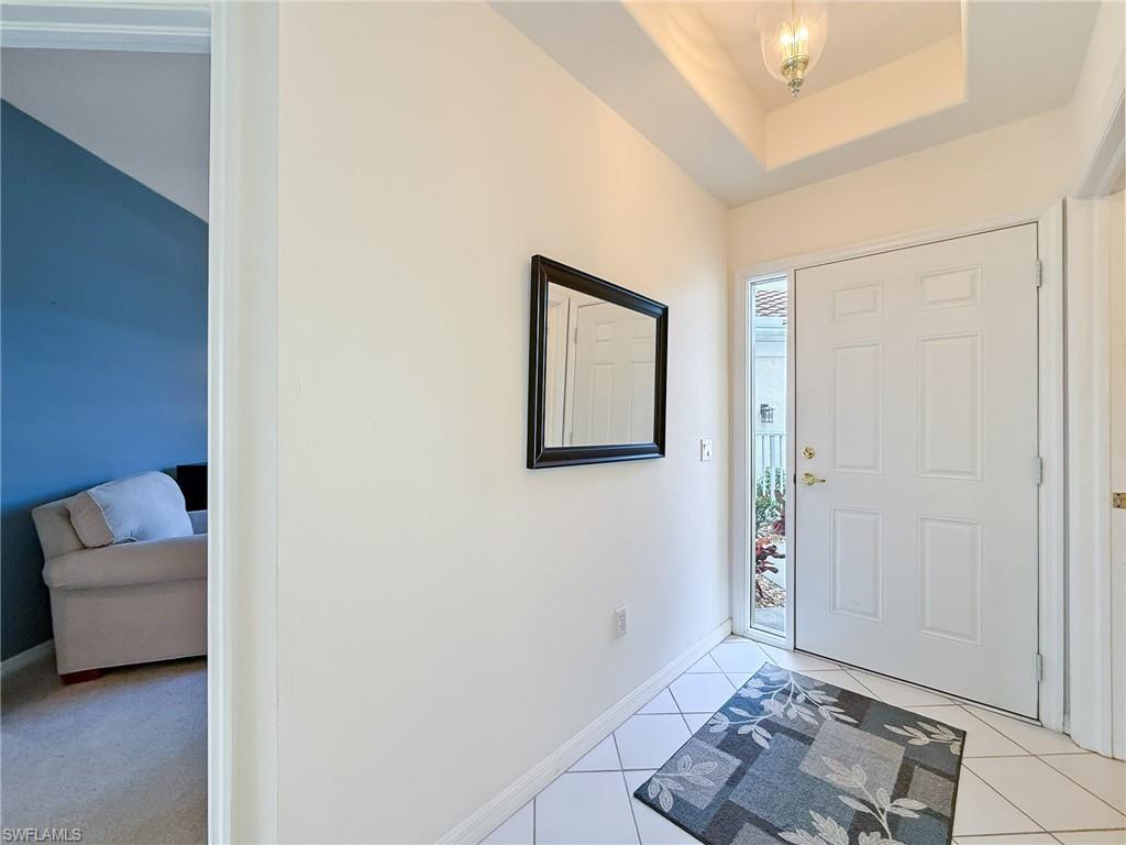 Image 4: Foyer entrance with baseboards, a tray ceiling, and light tile patterned floors