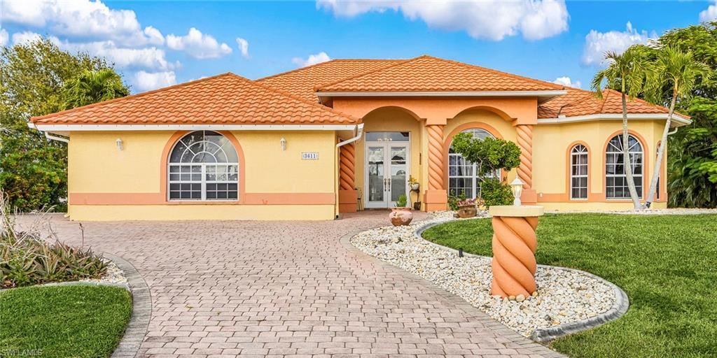 Image 1: Mediterranean / spanish-style home featuring french doors, a front lawn, stucco siding, and decorative driveway