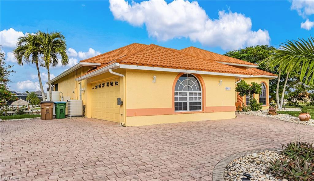 Image 3: View of side of home with decorative driveway, an attached garage, stucco siding, and a tile roof