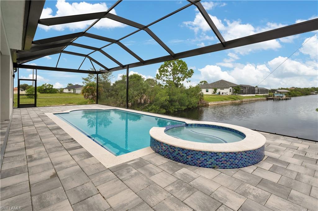 Image 2: View of swimming pool with a sunroom, a pool with connected hot tub, a patio area, a lanai, and a water view