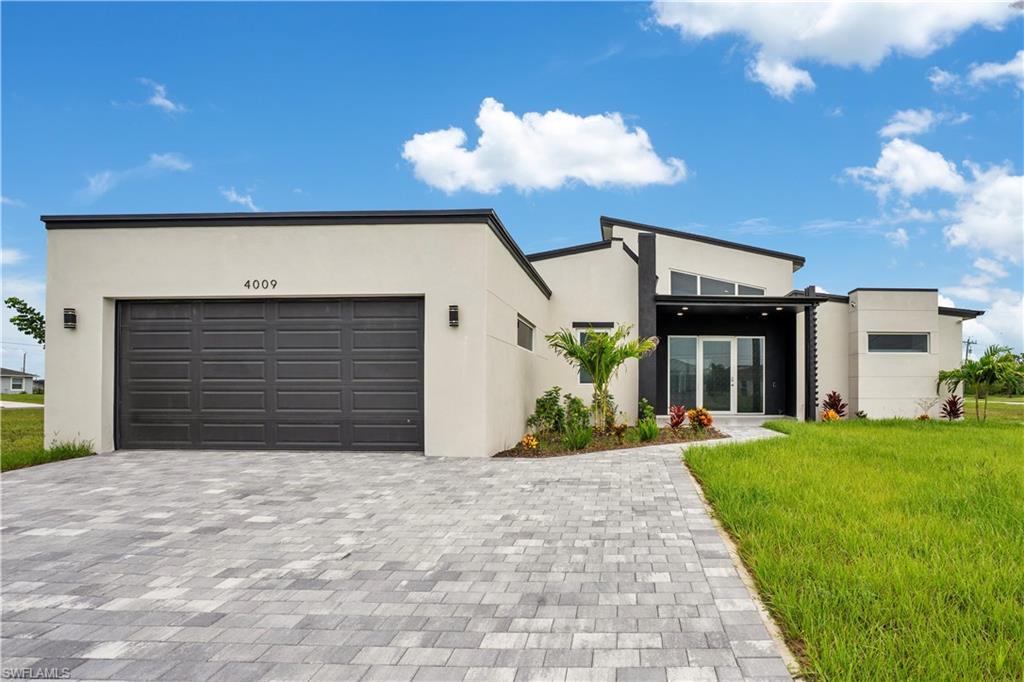 Image 3: View of front facade with decorative driveway, stucco siding, a front yard, and an attached garage