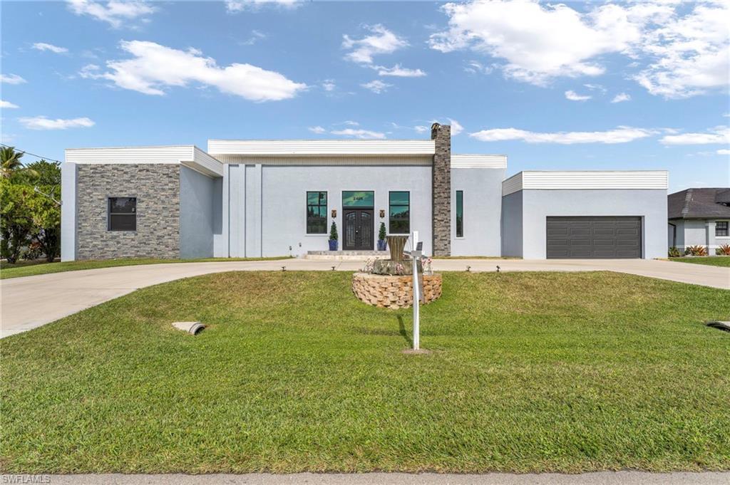 Image 1: Contemporary home with concrete driveway, stucco siding, a front lawn, and stone siding