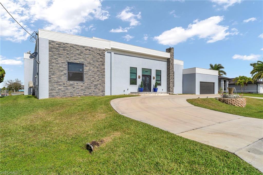 Image 2: Contemporary home with concrete driveway, a front yard, stucco siding, stone siding, and a chimney
