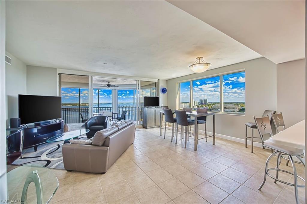 Image 3: Living area with light tile patterned floors, expansive windows, and ceiling fan
