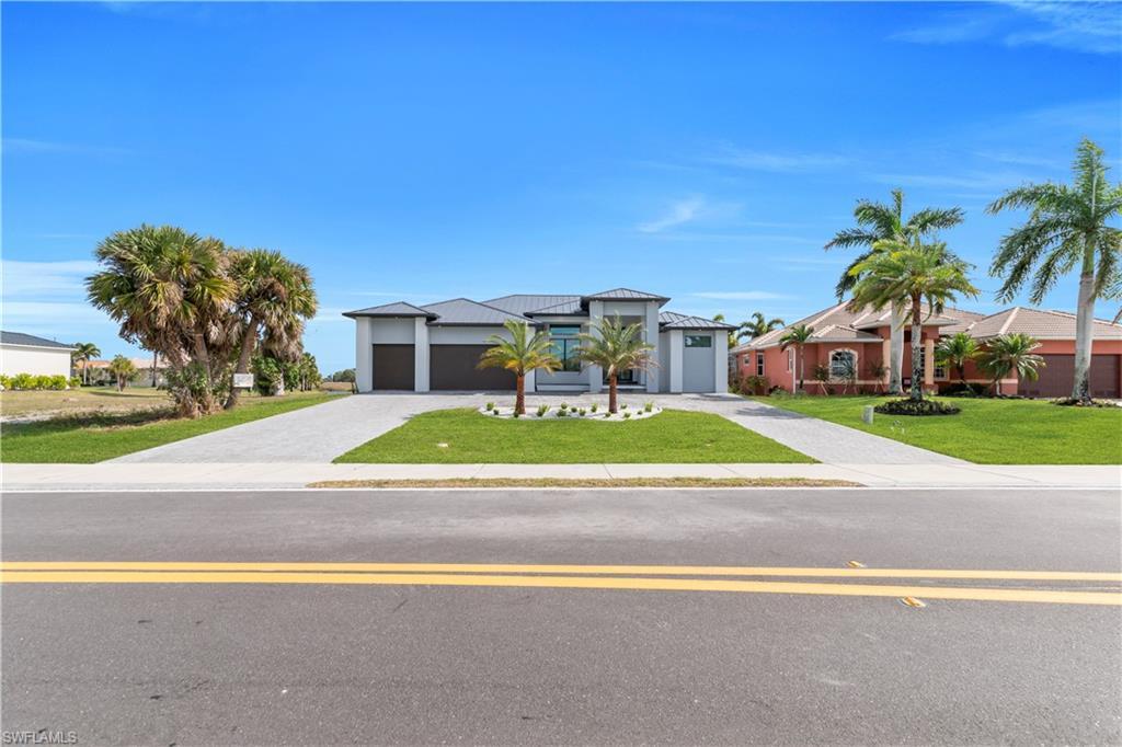 Image 2: View of front of property with a front yard, decorative driveway, an attached garage, and a metal roof
