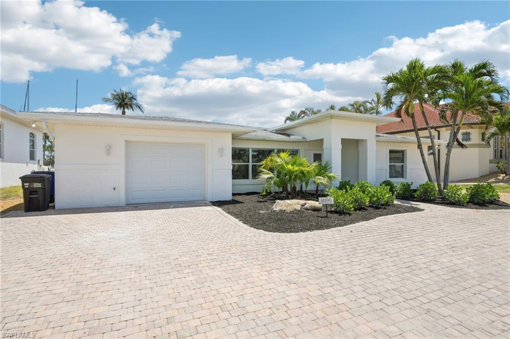 Image 3: View of front of home featuring an attached garage, decorative driveway, and stucco siding