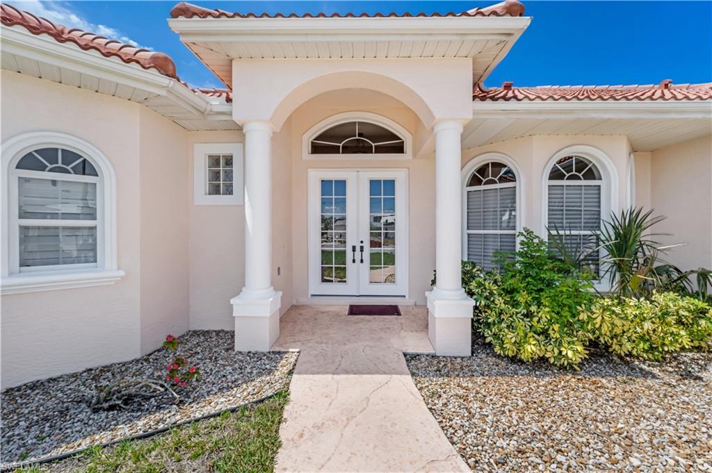 Image 2: Entrance to property with french doors, stucco siding, and a tile roof