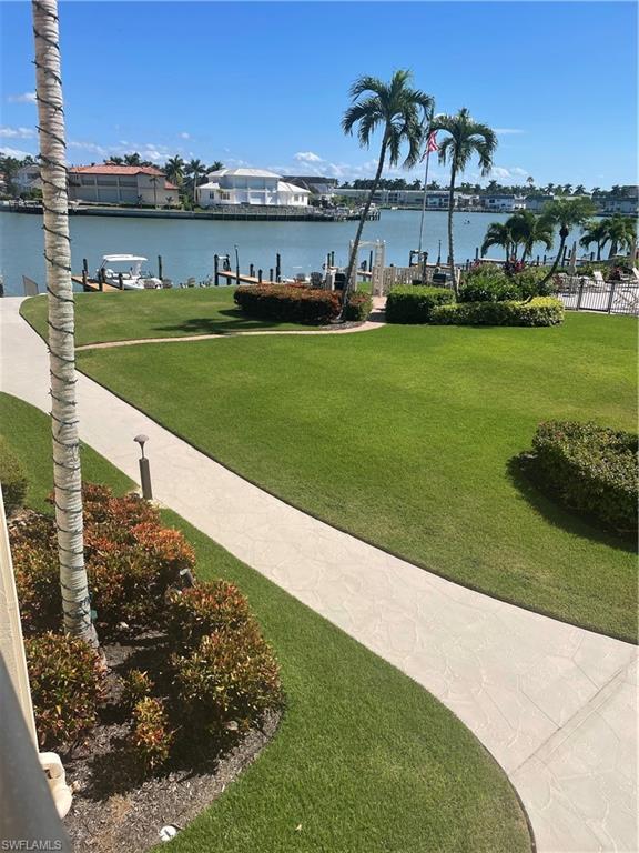 Image 2: Surrounding community with a yard, a water view, and a dock