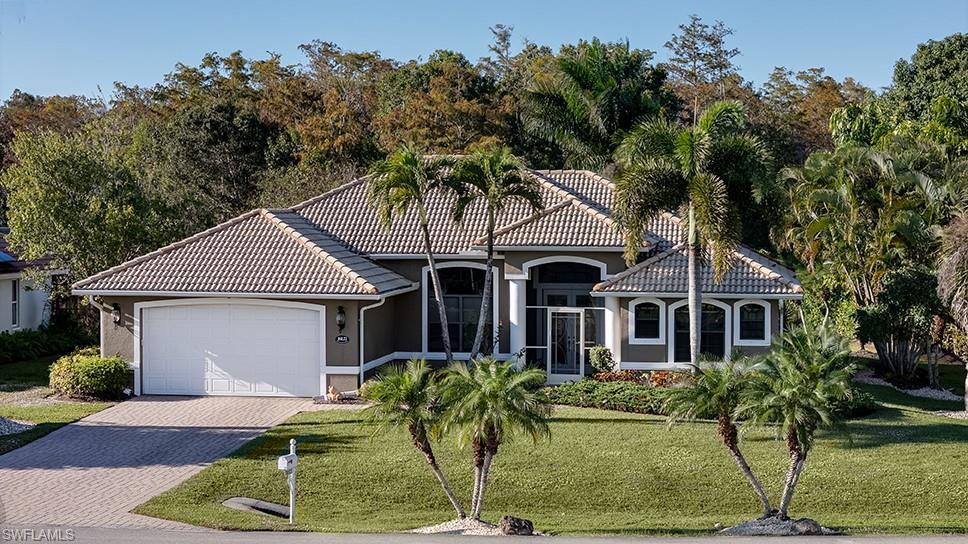 Image 1: Mediterranean style home featuring decorative driveway, a front yard, a garage, stucco siding, and a tile roof