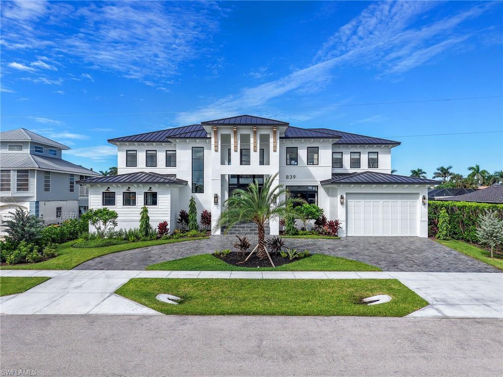 Image 1: View of front facade with a standing seam roof, a metal roof, decorative driveway, a garage, and stucco siding