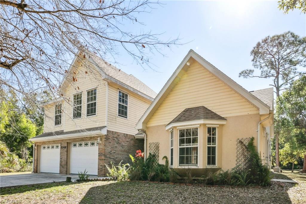 Image 1: View of front of home featuring an attached garage, brick siding, driveway, stucco siding, and a shingled roof
