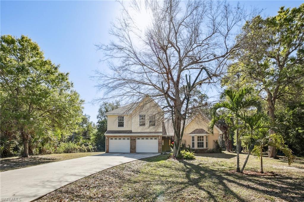 Image 2: View of front of home with an attached garage and long concrete driveway