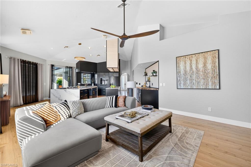 Image 3: Living room with light wood-style floors, a ceiling fan, and lofted ceiling