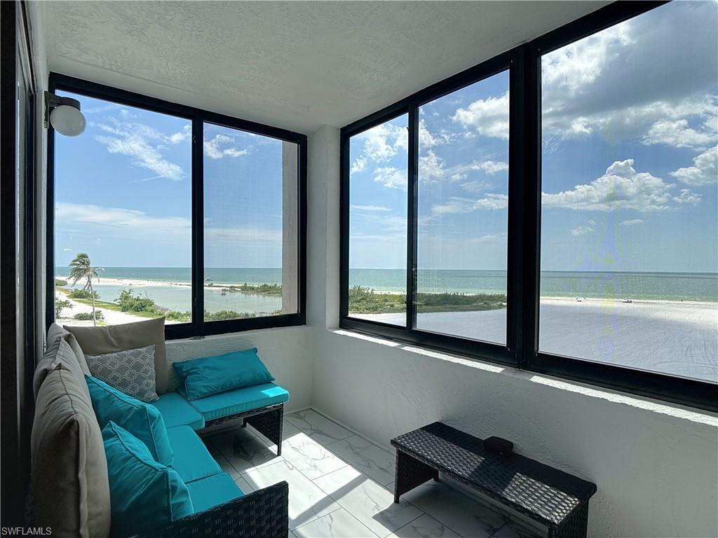 Image 3: Sunroom with marble look tile flooring, view of water and beach, a textured ceiling, and healthy amount of natural light