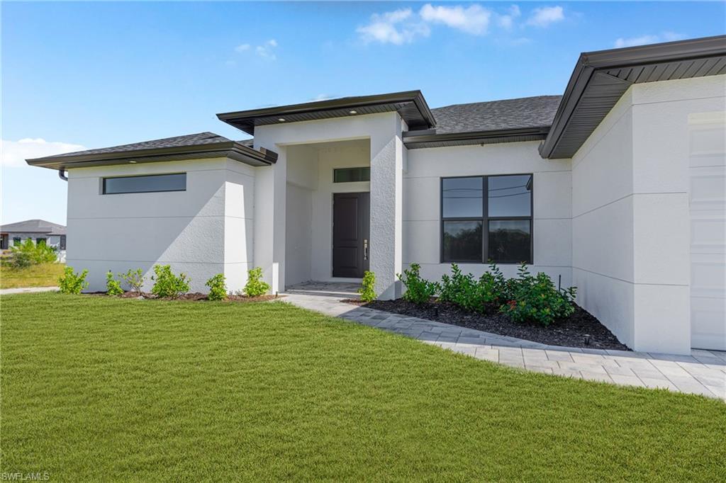 Image 1: Entrance to property featuring a lawn, stucco siding, and roof with shingles