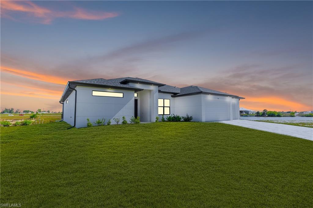 Image 3: View of front of home featuring driveway, a lawn, stucco siding, an attached garage, and a shingled roof