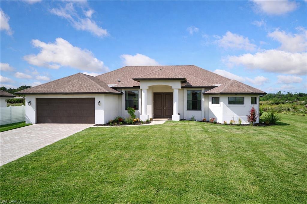 Image 2: View of front of property featuring stucco siding, a shingled roof, a front lawn, and driveway