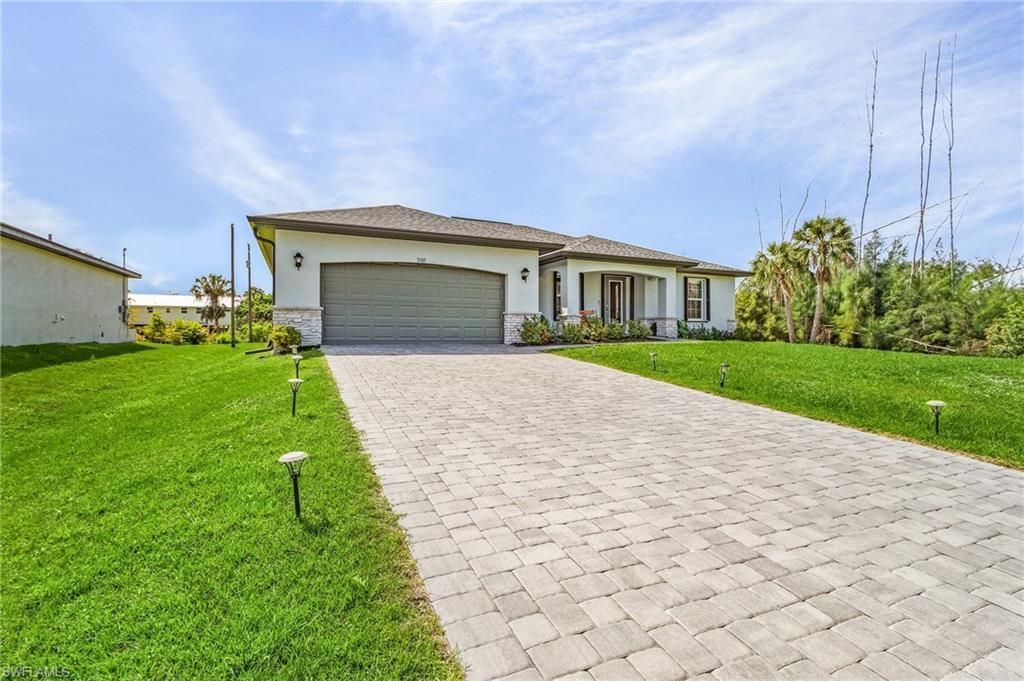 Image 1: Florida-style home featuring stucco siding, a front yard, decorative driveway, an attached garage, and covered porch