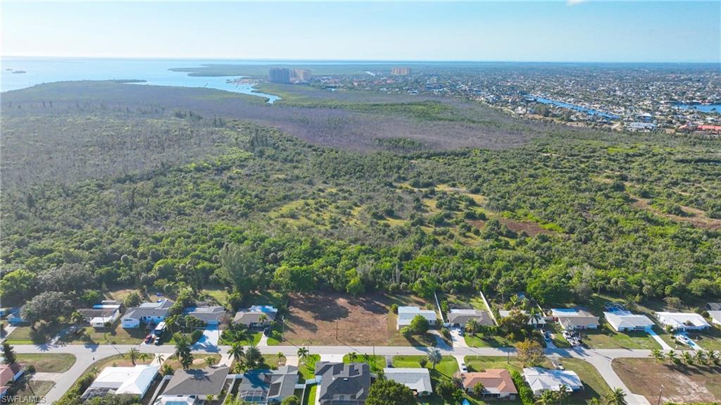 Image 1: Aerial perspective of suburban area featuring a nearby body of water and a heavily wooded area