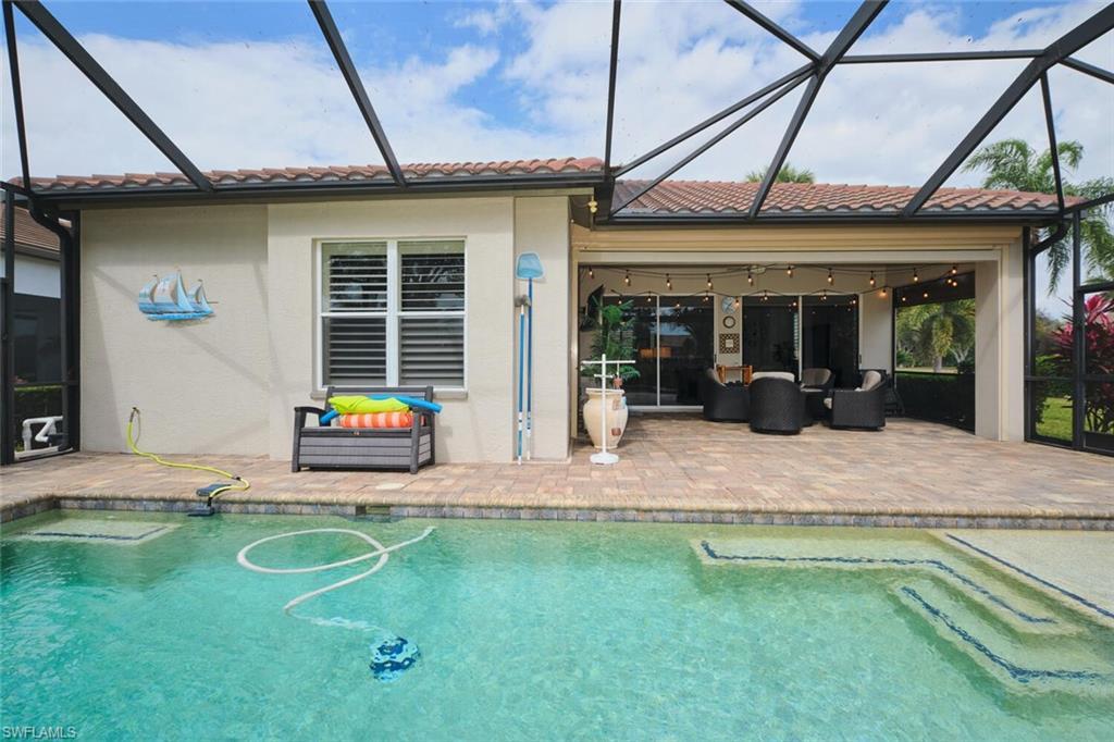 Image 4: Back of house featuring a sunroom, an outdoor pool, a patio, and a tiled roof