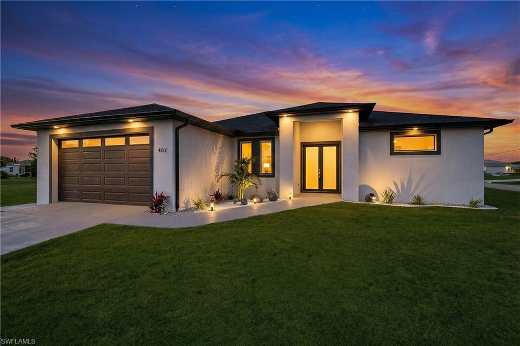 Image 2: Prairie-style house featuring a front lawn, a garage, concrete driveway, and stucco siding