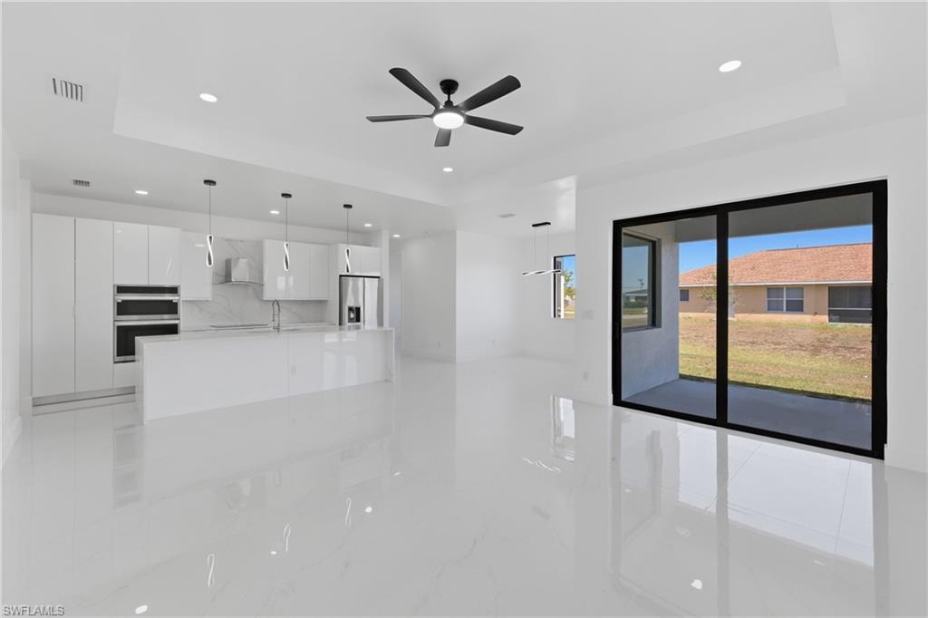 Image 4: Unfurnished living room featuring a raised ceiling, a ceiling fan, recessed lighting, and light marble finish floors