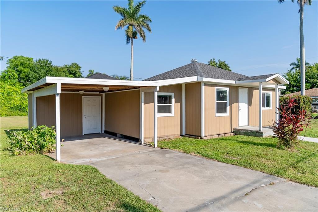 Image 2: View of front of property featuring a front lawn, an attached carport, concrete driveway, and a shingled roof