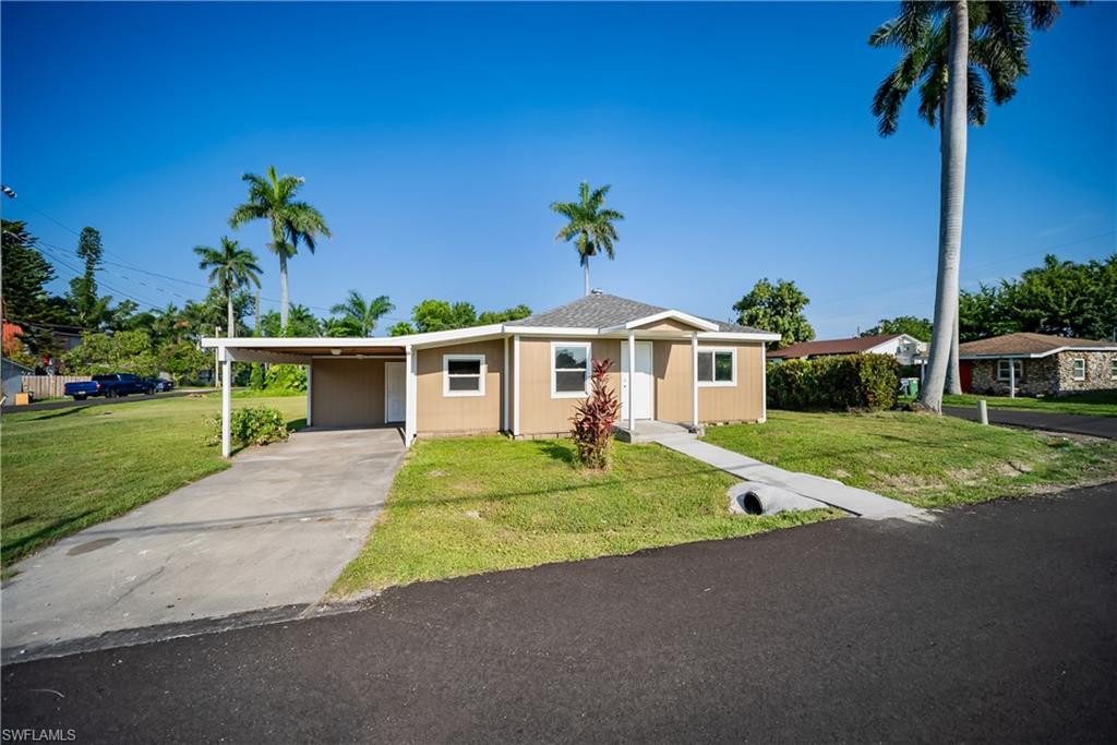 Image 4: View of front facade with a front lawn, concrete driveway, and a carport