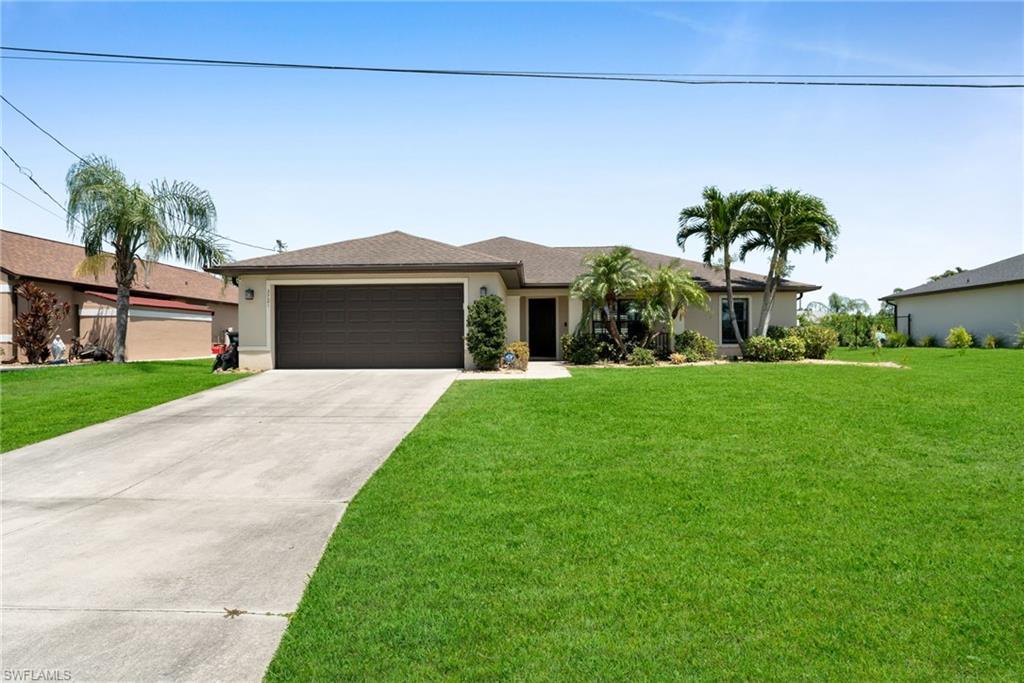Image 1: View of front of house with a garage, a front lawn, stucco siding, and driveway