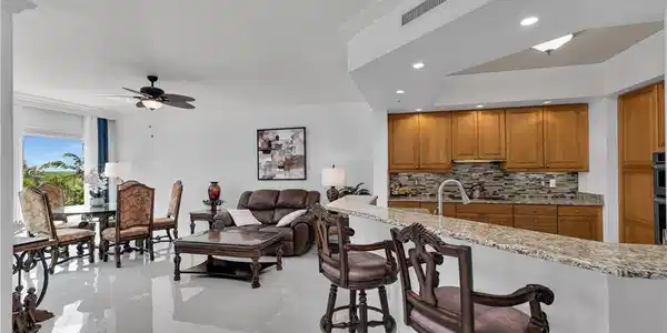 Image 3: Kitchen with crown molding, tasteful backsplash, light stone countertops, a breakfast bar area, and brown cabinets