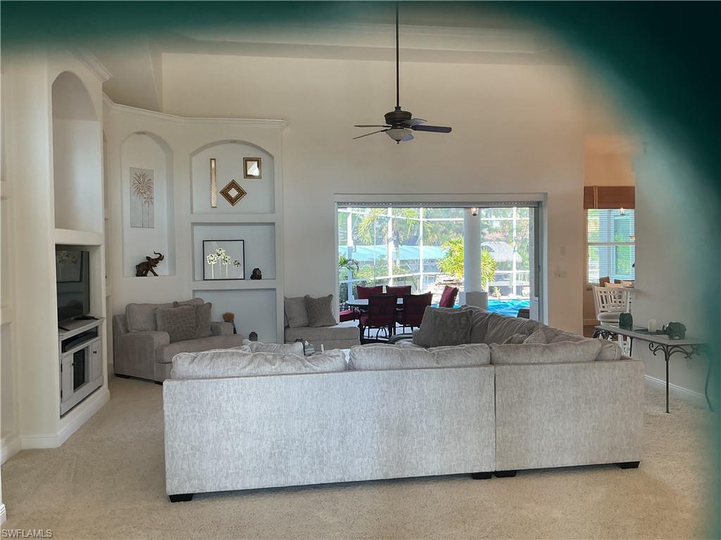 Image 3: Living area with a ceiling fan, a high ceiling, light colored carpet, and built in features