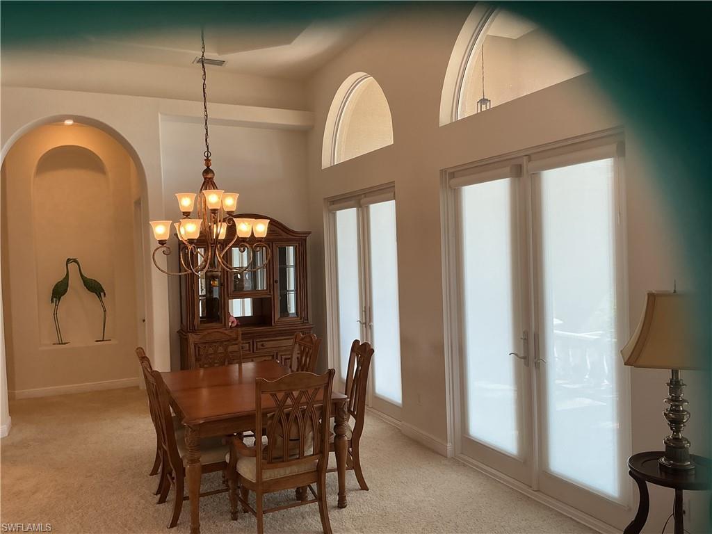 Image 4: Dining area with light carpet, suspended lighting, and a high ceiling