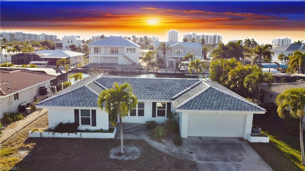 Image 1: View of front facade featuring a tiled roof, stucco siding, an attached garage, concrete driveway, and a city view