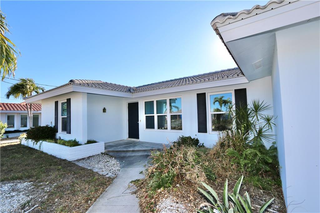 Image 4: Property entrance featuring a tiled roof and stucco siding