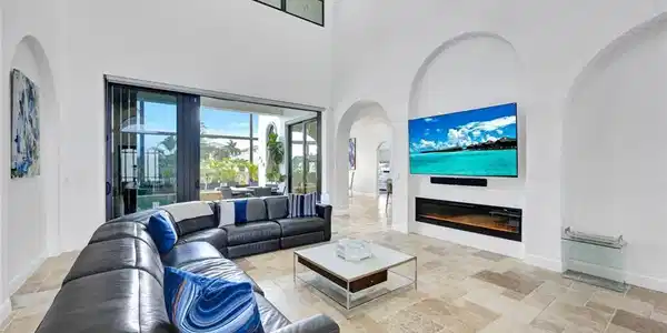 Image 2: Living area with stone tile flooring, a glass covered fireplace, arched walkways, and a high ceiling