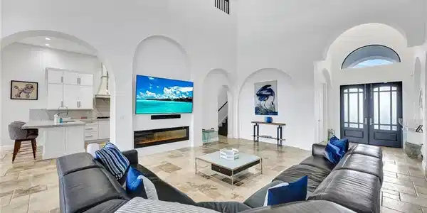 Image 3: Living area with stone tile flooring, arched walkways, a high ceiling, french doors, and a glass covered fireplace