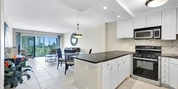 Image 4: Kitchen with electric range oven, stainless steel microwave, backsplash, and white cabinetry