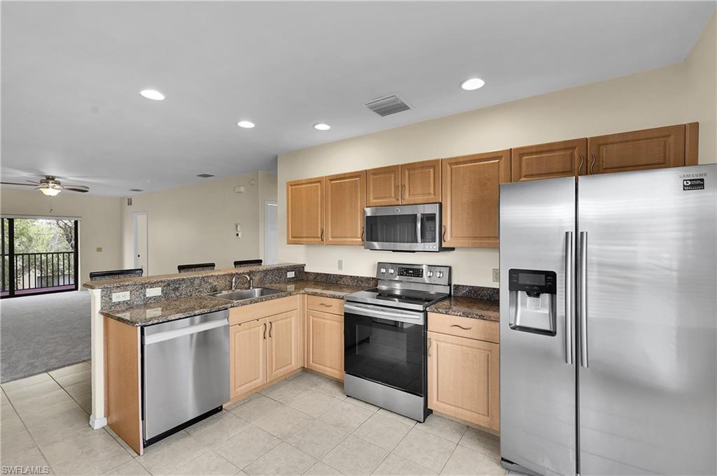 Image 3: Kitchen with appliances with stainless steel finishes, recessed lighting, open floor plan, light tile patterned flooring, and dark stone counters
