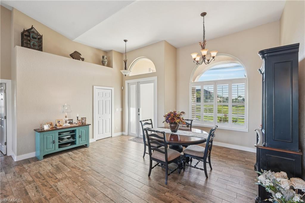 Image 3: Dining room with dark wood-style flooring, a high ceiling, and a chandelier
