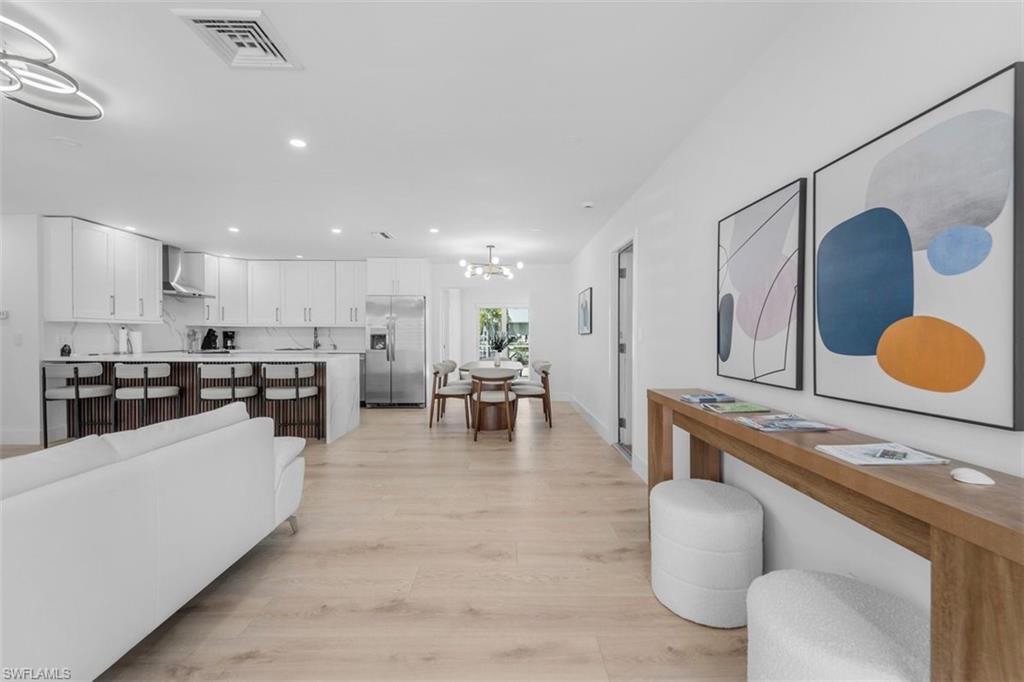 Image 4: Living area with light wood finished floors and hanging lights