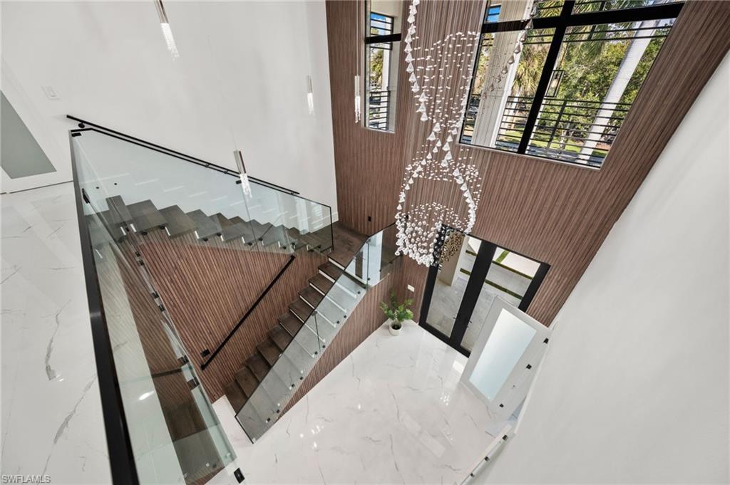 Image 3: Every detail has been thoughtfully curated&mdash;from oversized tile flooring and soaring ceilings with wood beam and shiplap accents to the modern wood-and-glass floating staircase and grand two-story entry foyer.