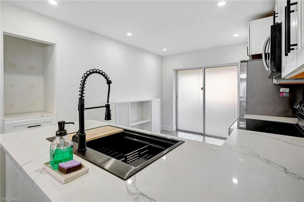 Image 4: Kitchen featuring light stone counters, recessed lighting, white cabinetry, and appliances with stainless steel finishes
