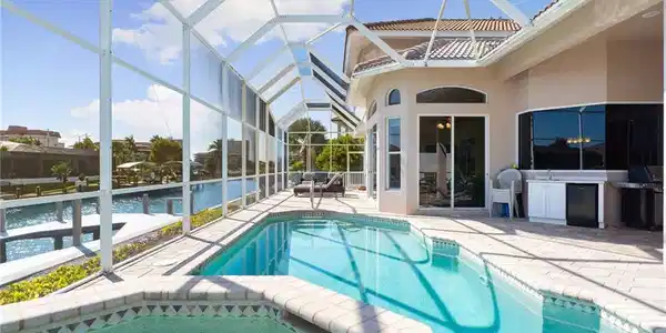 Image 2: Combined pool / hot tub featuring a sunroom, a patio area, glass enclosure, and area for grilling