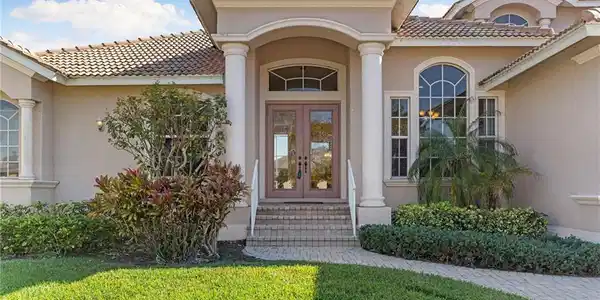 Image 3: Doorway to property with french doors, stucco siding, a lawn, and a tiled roof