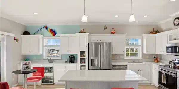 Image 4: Kitchen with appliances with stainless steel finishes, wine cooler, white cabinets, decorative light fixtures, and crown molding