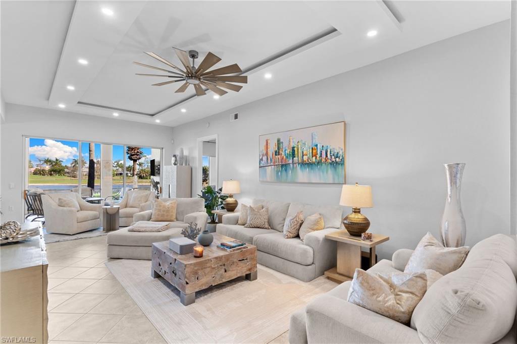 Image 3: Living area featuring a raised ceiling, ceiling fan, recessed lighting, and light tile patterned flooring