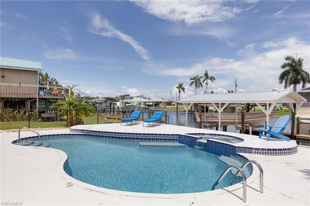Image 1: View of pool with a pool with connected hot tub, a sailboat access canal, view, and a patio area