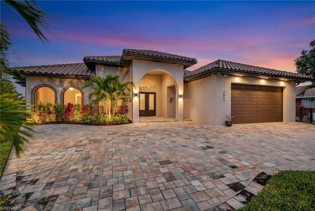Image 2: Mediterranean / spanish home featuring stucco siding, a garage, decorative driveway, a tile roof, and french doors