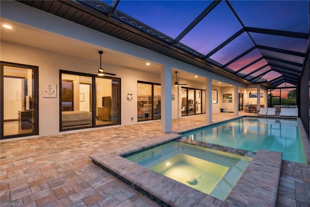 Image 4: View of swimming pool featuring a sunroom, a pool with connected hot tub, a patio, and glass enclosure